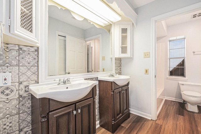 6307 Bayonne Dr, Spring, TX 77389 - full bathroom with two vanities, wood finished floors, toilet, and baseboards