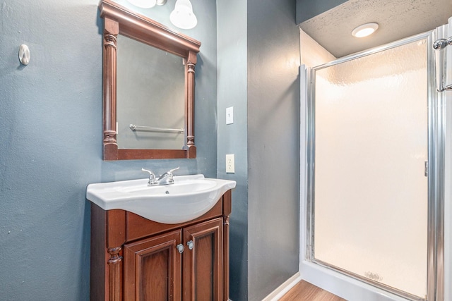 6307 Bayonne Dr, Spring, TX 77389 - full bathroom with a stall shower, vanity, baseboards, a textured wall, and wood finished floors