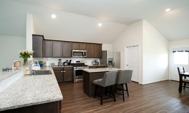 20202 Creekdale Bend Dr, Cypress, TX 77433 - kitchen with appliances with stainless steel finishes, a sink, dark brown cabinetry, a center island, and a breakfast bar