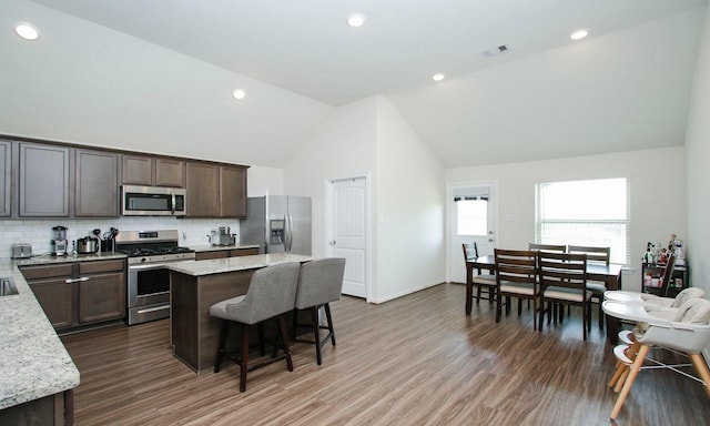 20202 Creekdale Bend Dr, Cypress, TX 77433 - kitchen with appliances with stainless steel finishes, a center island, a breakfast bar, decorative backsplash, and dark wood finished floors