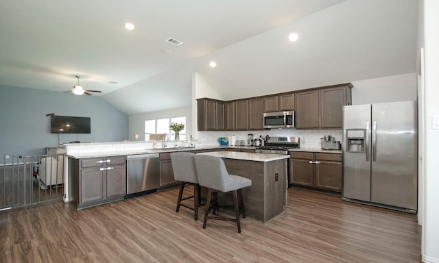20202 Creekdale Bend Dr, Cypress, TX 77433 - kitchen featuring appliances with stainless steel finishes, vaulted ceiling, dark wood-style floors, a peninsula, and a kitchen island