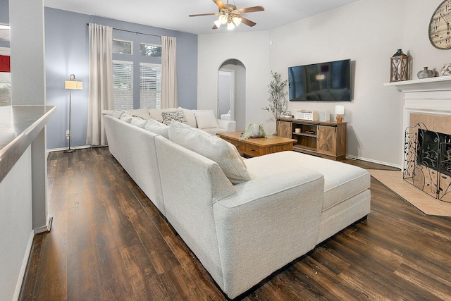 17206 Kobuk Valley Cir, Humble, TX 77346 - living room featuring arched walkways, dark wood-style floors, ceiling fan, a fireplace with flush hearth, and baseboards