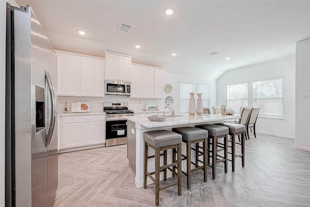 26414 Cooperstown Way, Splendora, TX 77372 - kitchen with appliances with stainless steel finishes, a kitchen bar, recessed lighting, white cabinets, and decorative backsplash