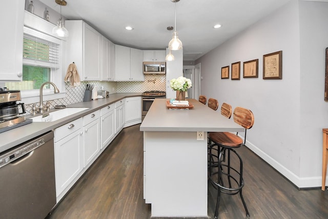 1038 Lawrence St, Houston, TX 77008 - kitchen with appliances with stainless steel finishes, a breakfast bar, tasteful backsplash, white cabinetry, and dark wood-type flooring