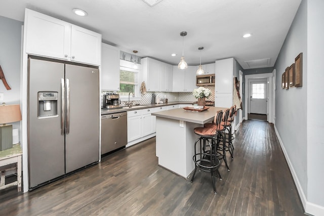 1038 Lawrence St, Houston, TX 77008 - kitchen with appliances with stainless steel finishes, white cabinets, dark wood-type flooring, a kitchen bar, and backsplash