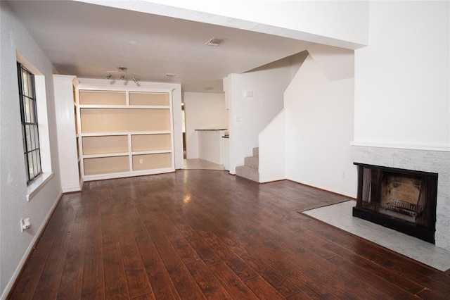 16800 Sugar Pine Dr Unit F44, Houston, TX 77090 - unfurnished living room with hardwood / wood-style flooring, a multi sided fireplace, stairs, and baseboards