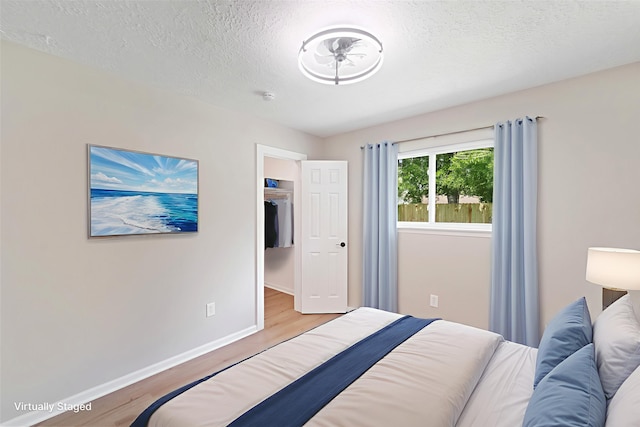 11114 Daybreak Ln, Cypress, TX 77429 - bedroom featuring light wood finished floors, baseboards, a textured ceiling, and a spacious closet