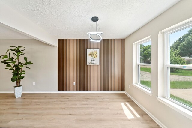 11114 Daybreak Ln, Cypress, TX 77429 - unfurnished dining area featuring light wood-style flooring, a textured ceiling, baseboards, and an accent wall