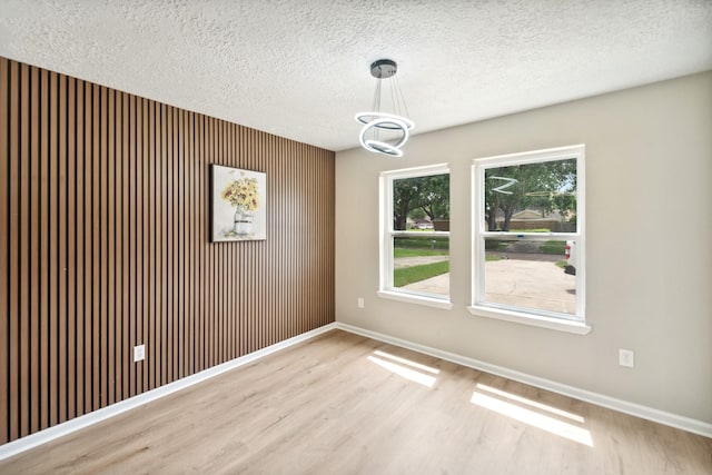 11114 Daybreak Ln, Cypress, TX 77429 - unfurnished dining area featuring wood finished floors, baseboards, a textured ceiling, a chandelier, and wooden walls