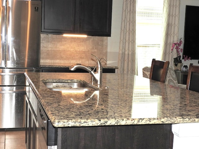 2705 Osprey Ln, Pearland, TX 77581 - kitchen featuring freestanding refrigerator, a sink, decorative backsplash, stone counters, and dark cabinetry