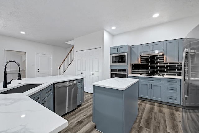 1826 Cheyenne River Cir, Sugar Land, TX 77478 - kitchen with appliances with stainless steel finishes, a sink, light stone counters, dark wood finished floors, and tasteful backsplash