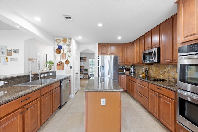 10711 Indian Trails Dr, Tomball, TX 77375 - kitchen featuring a sink, stainless steel appliances, dark stone counters, a center island, and arched walkways