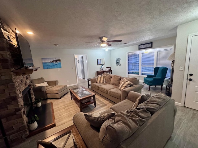 219 Lakeside Dr, Kemah, TX 77565 - living room featuring wood finished floors, a ceiling fan, a fireplace, baseboards, and a textured ceiling