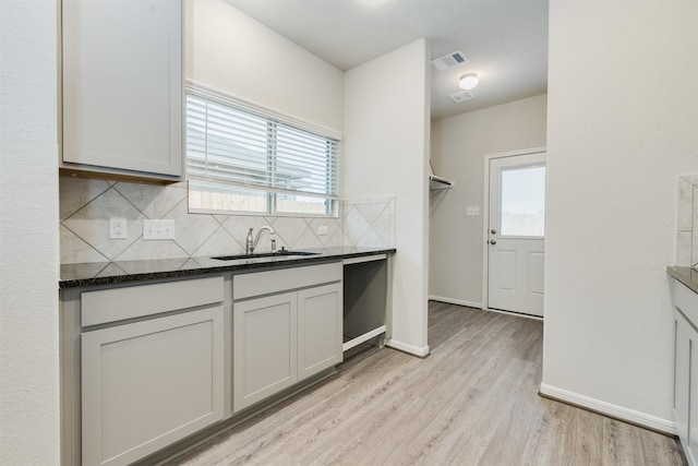 27398 Axis Deer Trl, Magnolia, TX 77354 - kitchen featuring a sink, decorative backsplash, light wood-style flooring, baseboards, and dark stone countertops