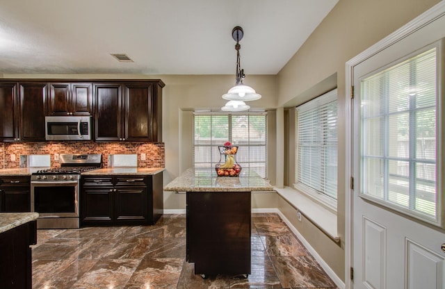 3203 Blaesser Dr, Pearland, TX 77584 - kitchen with stainless steel appliances, tasteful backsplash, pendant lighting, dark marble finish floors, and light stone counters