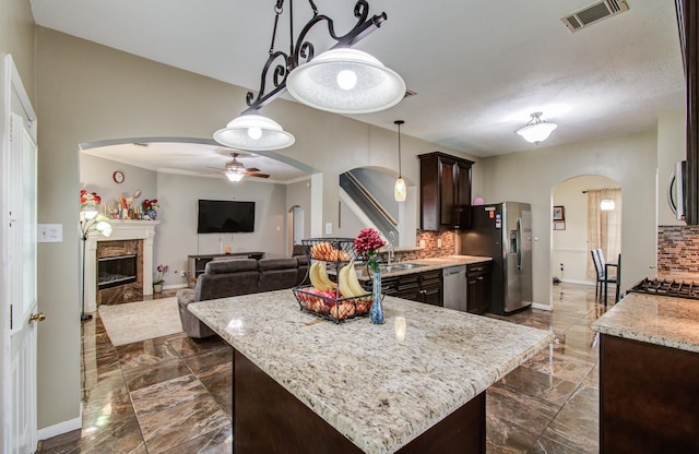 3203 Blaesser Dr, Pearland, TX 77584 - kitchen with arched walkways, appliances with stainless steel finishes, dark brown cabinets, ceiling fan, and tasteful backsplash