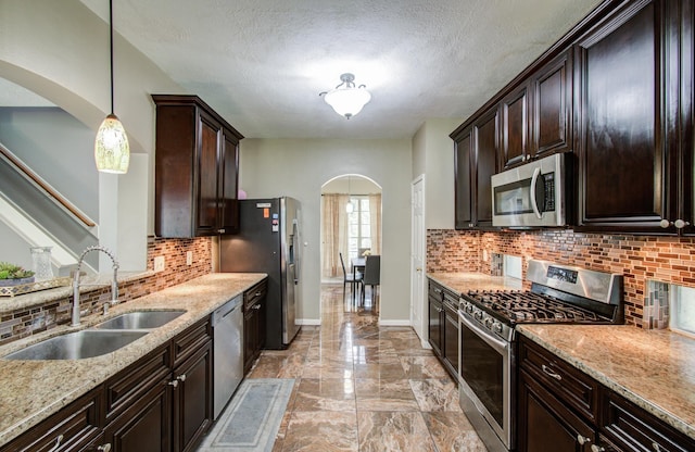 3203 Blaesser Dr, Pearland, TX 77584 - kitchen featuring appliances with stainless steel finishes, arched walkways, a sink, light marble finish floors, and backsplash