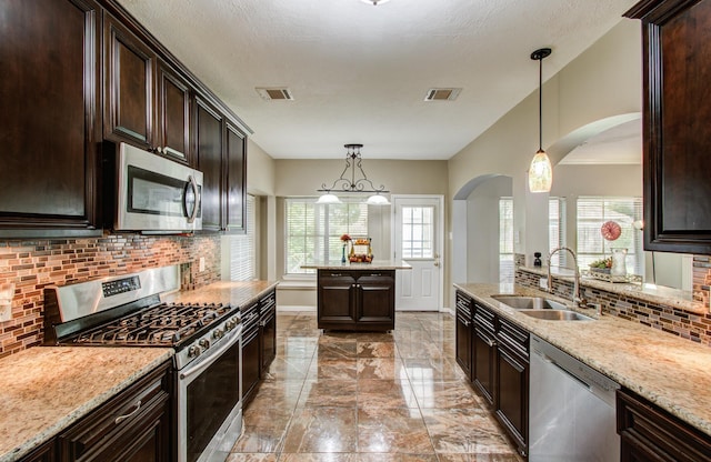 3203 Blaesser Dr, Pearland, TX 77584 - kitchen with appliances with stainless steel finishes, a sink, arched walkways, light marble finish flooring, and tasteful backsplash