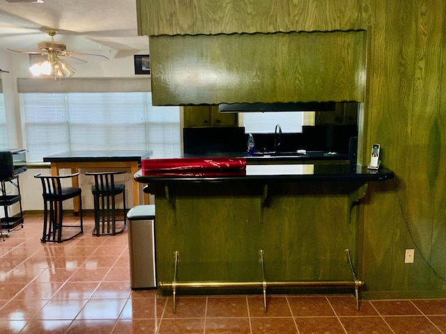 24360 Webb Rd, Porter, TX 77365 - kitchen with ceiling fan, dark countertops, a sink, tile patterned flooring, and a kitchen bar