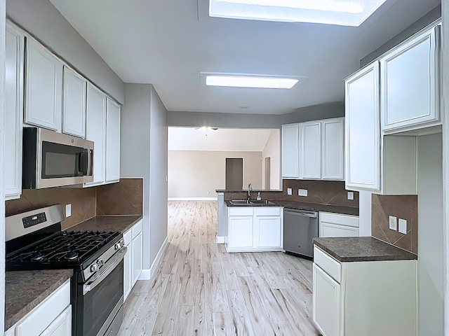 29375 Alba Rose Dr, Spring, TX 77386 - kitchen featuring appliances with stainless steel finishes, a sink, baseboards, light wood-style flooring, and dark countertops