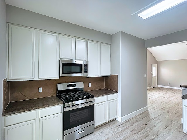 29375 Alba Rose Dr, Spring, TX 77386 - kitchen featuring stainless steel appliances, dark countertops, baseboards, white cabinetry, and lofted ceiling