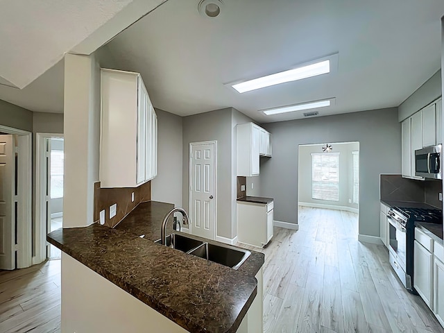 29375 Alba Rose Dr, Spring, TX 77386 - kitchen with appliances with stainless steel finishes, a sink, light wood-style flooring, a peninsula, and backsplash