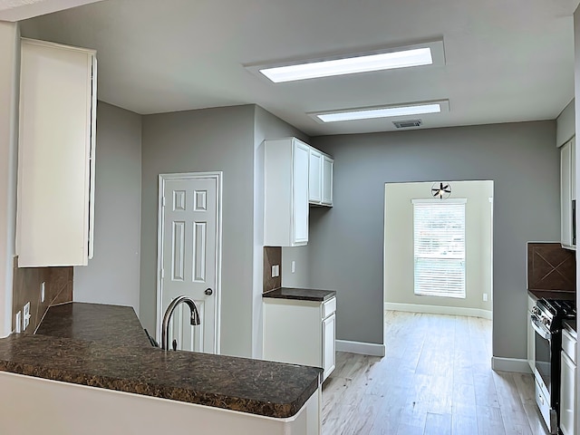 29375 Alba Rose Dr, Spring, TX 77386 - kitchen with gas range, light wood-type flooring, white cabinetry, a peninsula, and baseboards
