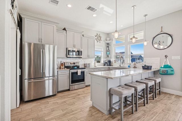 22212 Cantina Dr, Galveston, TX 77554 - kitchen featuring stainless steel appliances, a peninsula, a breakfast bar, light wood-style floors, and recessed lighting