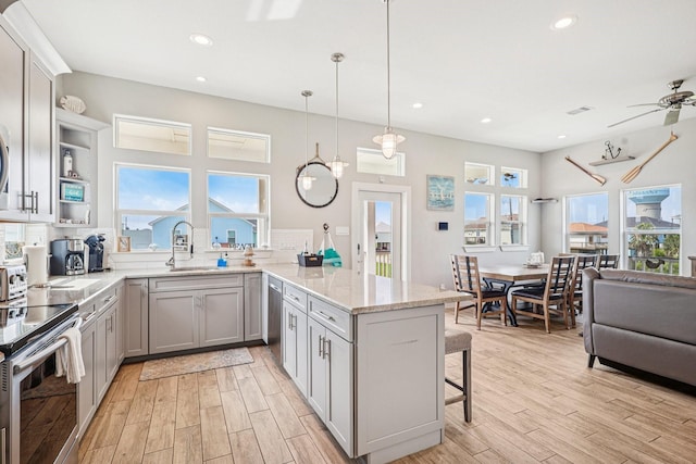 22212 Cantina Dr, Galveston, TX 77554 - kitchen with a peninsula, stainless steel appliances, a kitchen bar, light wood-style flooring, and a ceiling fan