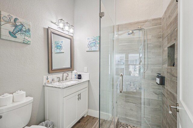 22212 Cantina Dr, Galveston, TX 77554 - full bathroom featuring vanity, a shower stall, a textured wall, and wood finished floors