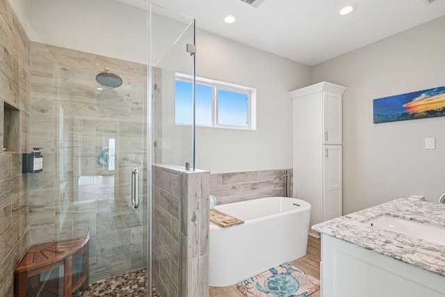 22212 Cantina Dr, Galveston, TX 77554 - bathroom with a freestanding tub, vanity, a stall shower, wood finished floors, and tile walls