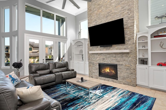 211 Valmar St, Kemah, TX 77565 - living area featuring ceiling fan, light tile patterned flooring, a stone fireplace, ornamental molding, and healthy amount of natural light