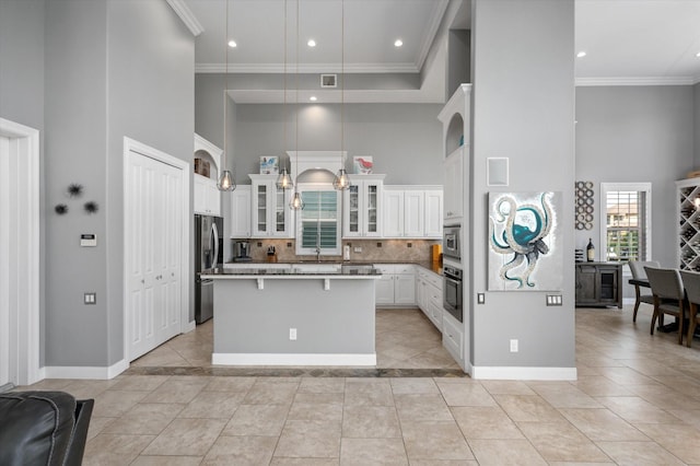 211 Valmar St, Kemah, TX 77565 - kitchen featuring a high ceiling, stainless steel appliances, a center island, baseboards, and white cabinets