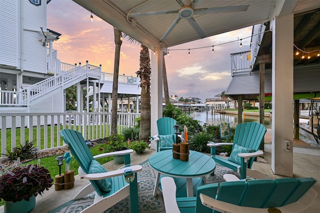 3906 Bridge Harbor Dr, Galveston, TX 77554 - patio terrace at dusk with stairs, a ceiling fan, a water view, and a patio area
