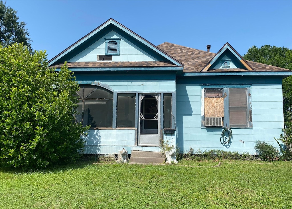 9910 Fulton St, Houston, TX 77076 - bungalow-style house with a front lawn, a sunroom, entry steps, roof with shingles, and cooling unit