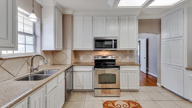 4208 Walker St, Houston, TX 77023 - kitchen with stainless steel appliances, a sink, white cabinets, light tile patterned floors, and arched walkways