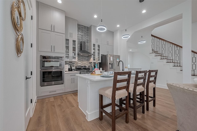 1305 E 27th St Unit A, Houston, TX 77009 - kitchen with stainless steel appliances, wall chimney exhaust hood, light wood-type flooring, light countertops, and recessed lighting