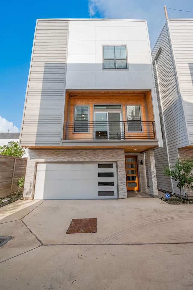 1305 E 27th St Unit A, Houston, TX 77009 - contemporary home featuring a garage, a balcony, driveway, and stone siding