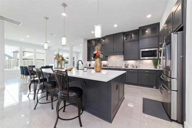 11023 White Caterpillar Dr, Cypress, TX 77433 - kitchen featuring appliances with stainless steel finishes, backsplash, light countertops, a center island with sink, and a sink