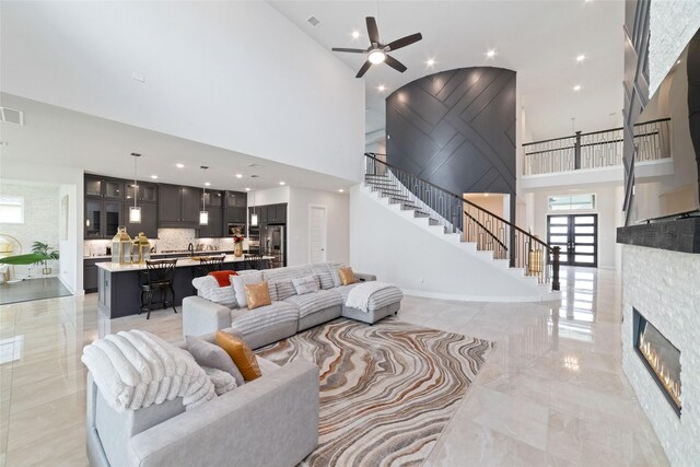 11023 White Caterpillar Dr, Cypress, TX 77433 - living area with a high ceiling, stairway, ceiling fan, light marble finish floors, and a fireplace