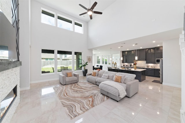 11023 White Caterpillar Dr, Cypress, TX 77433 - living area featuring ceiling fan, a high ceiling, healthy amount of natural light, a stone fireplace, and baseboards