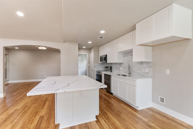 12406 Whittington Dr, Houston, TX 77077 - kitchen featuring appliances with stainless steel finishes, a sink, arched walkways, a center island, and backsplash