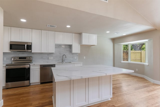 12406 Whittington Dr, Houston, TX 77077 - kitchen with stainless steel appliances, a sink, light wood-type flooring, backsplash, and white cabinets