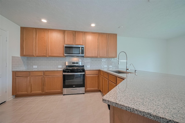 12327 Buck Sable Ln, Houston, TX 77044 - kitchen featuring stainless steel appliances, decorative backsplash, a peninsula, light stone counters, and recessed lighting