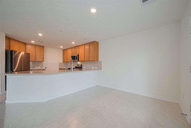 12327 Buck Sable Ln, Houston, TX 77044 - kitchen with appliances with stainless steel finishes, tasteful backsplash, light stone countertops, recessed lighting, and a peninsula
