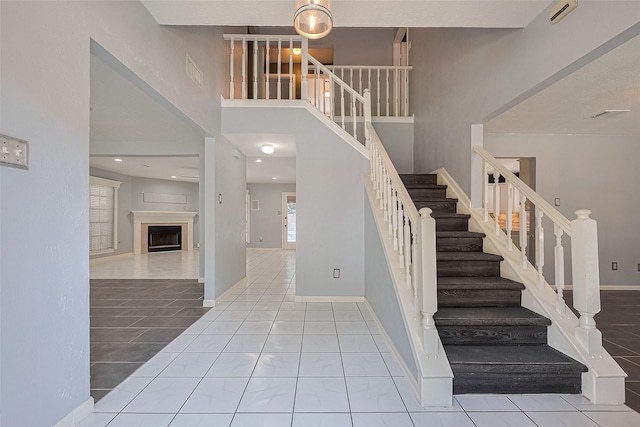 3718 Sweetgum Hill Ln, Houston, TX 77345 - stairway featuring baseboards, tile patterned floors, a fireplace, and a towering ceiling