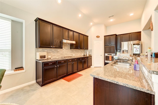 6119 Cresting Knolls Cir, Richmond, TX 77407 - kitchen featuring stainless steel appliances, tasteful backsplash, dark brown cabinetry, under cabinet range hood, and light stone counters