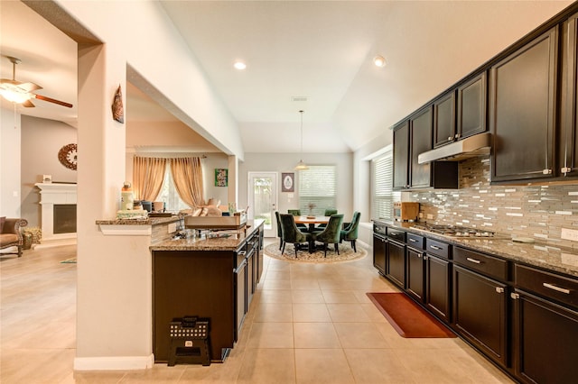 6119 Cresting Knolls Cir, Richmond, TX 77407 - kitchen featuring light stone countertops, ceiling fan, dark brown cabinets, vaulted ceiling, and backsplash