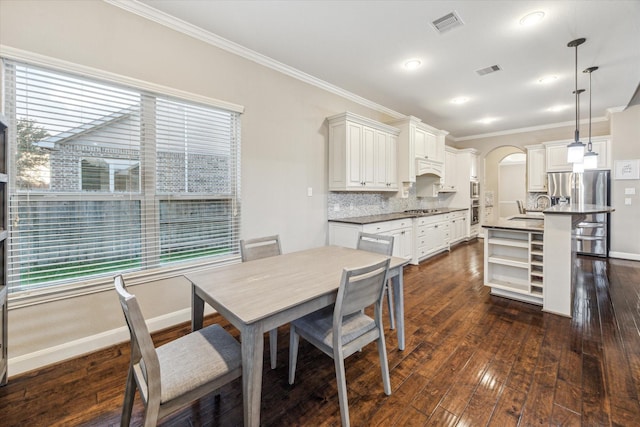6815 Cottonwood Crest Ln, Katy, TX 77493 - dining space featuring ornamental molding, arched walkways, healthy amount of natural light, dark wood finished floors, and baseboards
