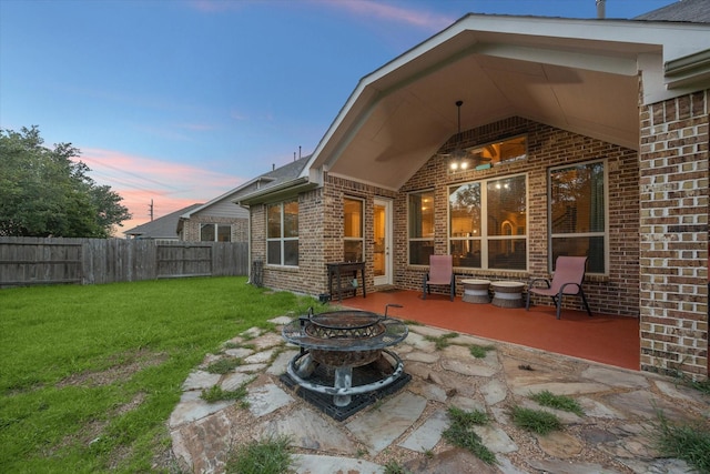 6815 Cottonwood Crest Ln, Katy, TX 77493 - back of property at dusk featuring an outdoor fire pit, brick siding, and a patio area